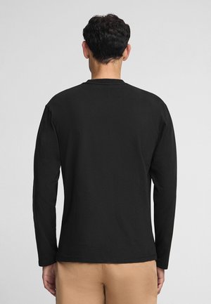 Zwarte T-shirt met lange mouwen van katoen, voorzien van een ronde halslijn en een zachte textuur, gedragen met lichte broek.