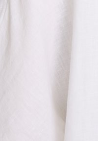 Valkoinen pellavakangas, joka esittelee pehmeän, teksturoidun pinnan, jossa on hienovarainen kudontakuvio. Materiaali näyttää kevyeltä ja ilmavalta.