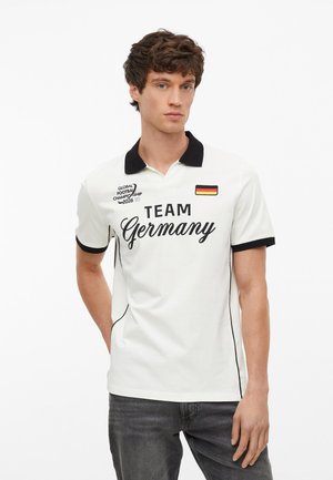 Młody mężczyzna ubrany w białą koszulkę polo z czarnym kołnierzem i napisem „Team Germany”, z naszywką niemieckiej flagi i logo Global Football Championship 2026.