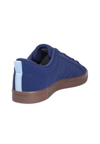 Tummansininen lenkkari, jossa on sileä pinta, erottuva vaaleansininen takanappi ja ruskea kumipohja. Sisältää sivusaumauksen design-yksityiskohtana.