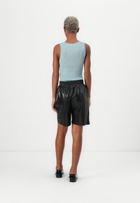 Lichtblauwe geribbelde tanktop met een aansluitend ontwerp, gecombineerd met zwarte leren shorts, voorzien van een elastische tailleband en een gladde textuur.