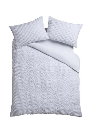 Weißes strukturiertes Steppbett und zwei passende Kissen auf einem Bett mit einer Ecke der Decke zurückgefaltet.