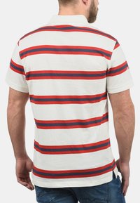 Gestreepte polo shirt met horizontale rode en marineblauwe strepen op een witte achtergrond. Korte mouwen met een ribgebreide kraag en zijventilaties.