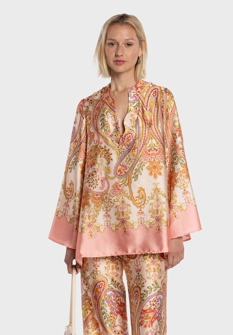 Blouse en soie à motif cachemire aux couleurs vives, présentant un col montant et des manches cloche, assortie à un pantalon au motif identique.