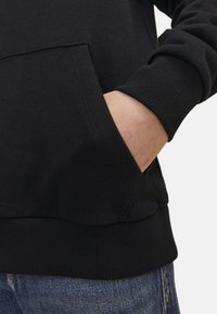 Black sweatshirt with a front pocket, ribbed cuffs, and hem, made of soft fabric. Visible stitching detail near the pocket area.