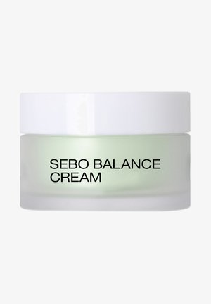 Crema Sebo Balance en un tarro de vidrio esmerilado con tapa blanca; crema verdosa visible en el interior; texto negro en negrita en la etiqueta frontal.