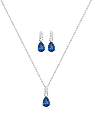 Collier en argent avec un pendentif en pierre précieuse bleue en forme de goutte, orné de pierres d'accent transparentes au-dessus. Boucles d'oreilles assorties au design similaire.
