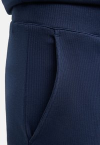 Nahaufnahme eines marineblauen, gerippten Stoffes von Sweatpants mit sichtbaren Nähten und Bündchen.
