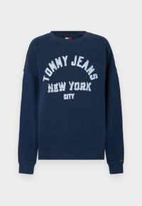 Felpa blu navy con la scritta "TOMMY JEANS NEW YORK CITY" stampata in grande testo bianco. Presenta un collo a giro e polsini a coste.