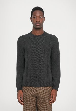 Dunkelgrauer Strickpullover mit strukturiertem Mittelteil und geripptem Ausschnitt. Lange Ärmel und figurbetonter Saum, getragen mit karierter brauner Hose.