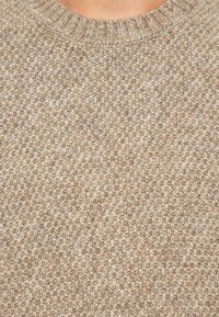 Beige knitted sweater with a textured pattern, featuring a classic crew neckline and varying shades of tan and cream throughout.