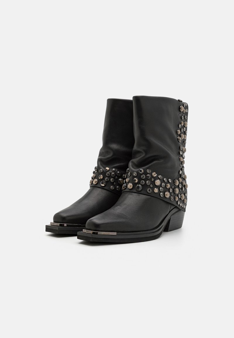 Botas de cuero negras hasta el tobillo con un diseño arrugado, adornadas con tachuelas plateadas alrededor del tobillo y un tacón bajo en capas.