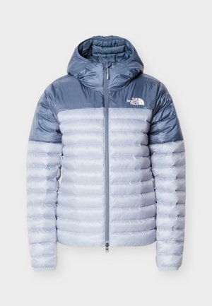 Giacchetto imbottito leggero con cappuccio, caratterizzato da un design bicolore in azzurro chiaro e scuro, texture trapuntata, zip frontale e logo sul petto.