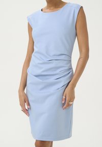Světle modré přiléhavé šaty s krátkými rukávy, s nařasenou látkou na jedné straně a hladkou texturou, délka po kolena.