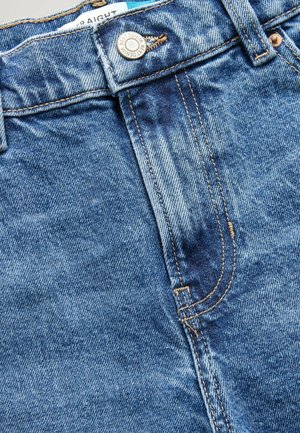 Blå denim jeans med lige pasform, der har kobbernitter, gyldne syninger og en slidt overflade. Inkluderer knaplukning og bæltesløjfer.