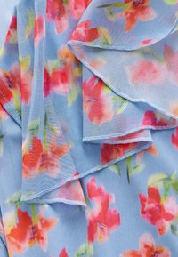 Transparenter, hellblauer Stoff mit einem floralen Muster in Rosa- und Orangetönen. Mit sanften Rüschen und zarter Naht entlang der Ränder.