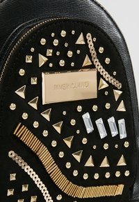 Sac texturé noir avec clous géométriques dorés, paillettes, cristaux rectangulaires et plaque étiquette dorée "River Island".