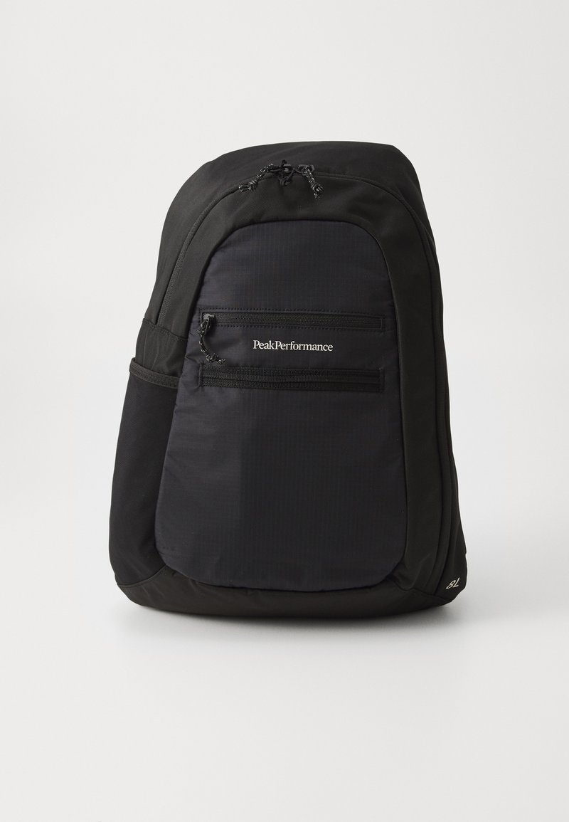 Mochila preta com um acabamento liso, apresentando um bolso frontal com fecho éclair e o logótipo "PeakPerformance" na frente. Forma arredondada.
