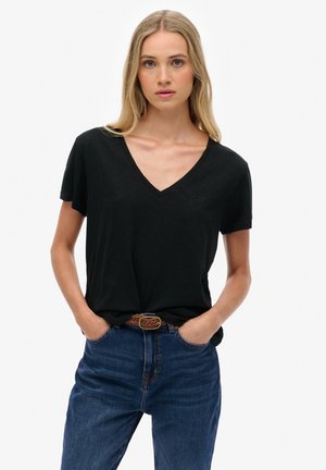 Zwarte V-hals t-shirt van zachte stof, korte mouwen, met een relaxte pasvorm, gecombineerd met hoge blauwe denim jeans en een bruine gevlochten riem.