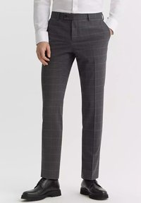 Szare kraciaste spodnie o slim fit, wykonane z teksturowanej tkaniny, z płaskim przodem i bocznymi kieszeniami, zestawione z czarnymi eleganckimi butami.