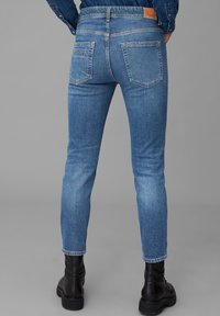 Vaaleansiniset farkut slim fit -mallia, joissa on takataskut, hillitty kulutusjälki ja nahkapaikka vyötäröllä.