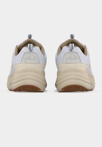 Ζευγάρι λευκά και μπεζ αθλητικά παπούτσια FILA, εμφανιζόμενα από πίσω με χοντρές μπεζ σόλες και γκρι ιμάντες έλξης, σε λευκό φόντο.