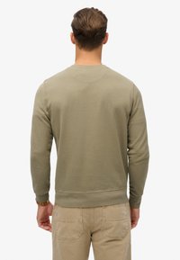 Olivengroene sweatshirt met lange mouwen, geribbelde manchetten en zoom, en een ronde hals, gezien van achteren tegen een witte achtergrond.
