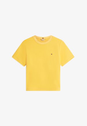 Tricou galben cu mâneci scurte și guler rotund, cu un mic logo dreptunghiular brodat în roșu, alb și albastru pe partea stângă a pieptului.