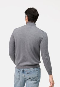 Grauer Pullover mit hohem Kragen, gerippten Ärmeln und Saum. Hergestellt aus weichem Material, mit glatter Textur und figurbetontem Design.