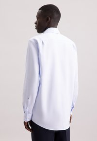 Camicia azzurra a maniche lunghe in tessuto liscio, con colletto classico, polsini con bottone e dettagli di sartoria discreti sul retro.