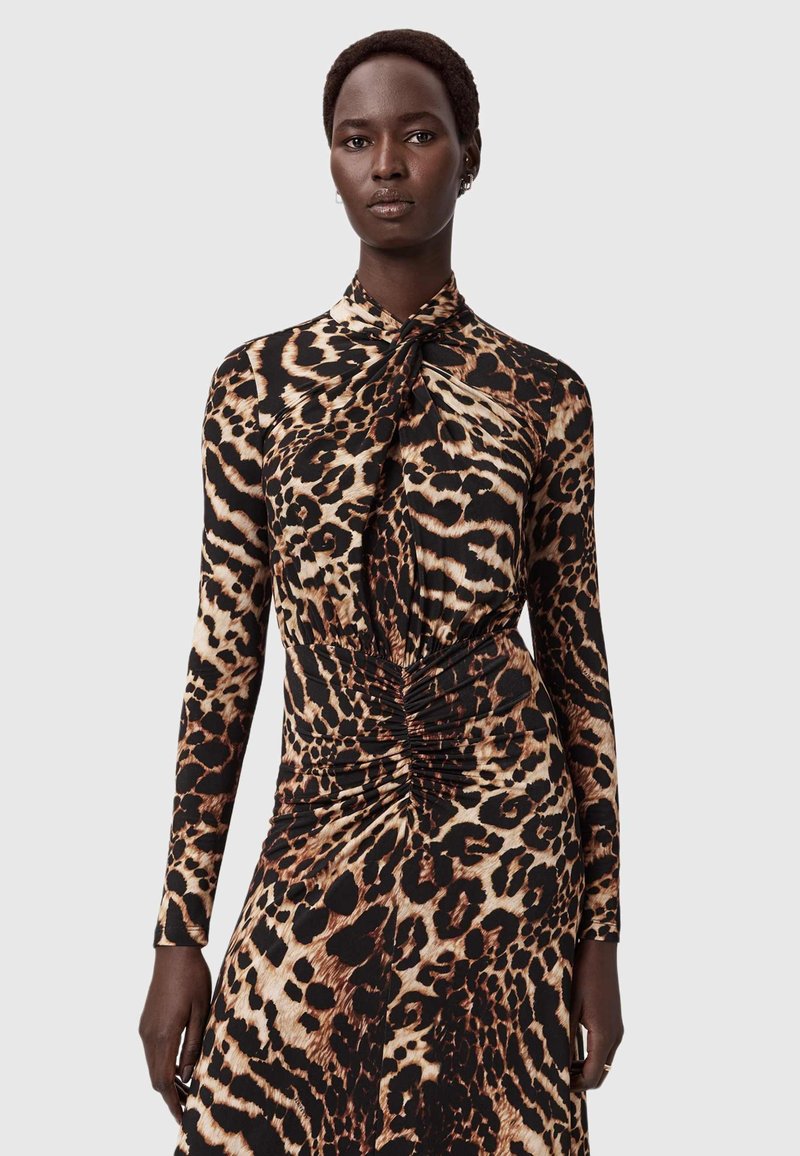 Langsleevige jurk met een luipaardprint in bruin en zwart, voorzien van een geknoopte kraag en een gathering in de taille, gemaakt van een soepel stof.