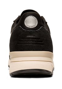 Black sneaker featuring a mix of suede and mesh materials, a textured heel cap, and a cream-colored midsole with a rubber outsole.