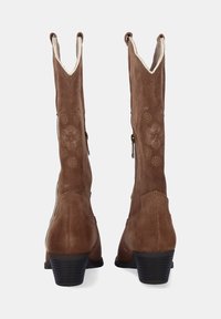 Botas de ante marrón hasta la rodilla con un ligero tacón, que presentan un patrón floral decorativo y un cierre de cremallera en el costado.