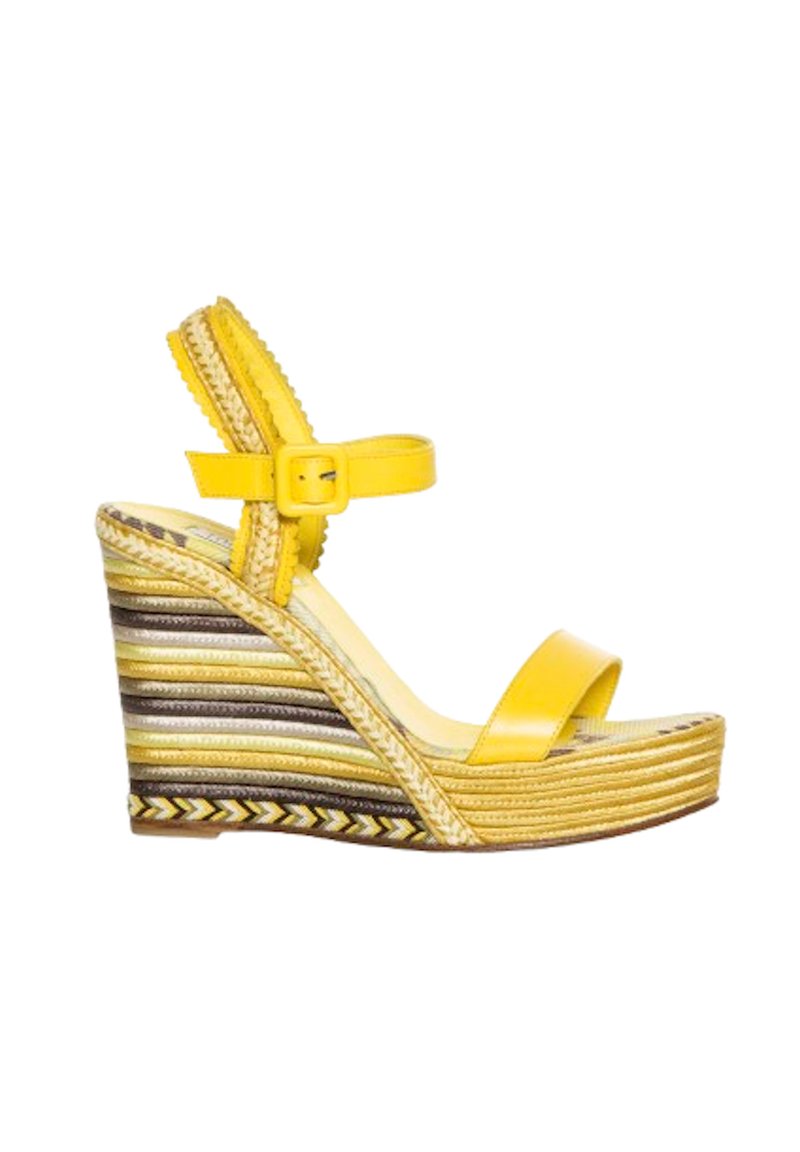 Sandalia cuña amarilla con una tira ancha sobre los dedos, correa ajustable en el tobillo y plataforma tejida texturizada de varios colores.