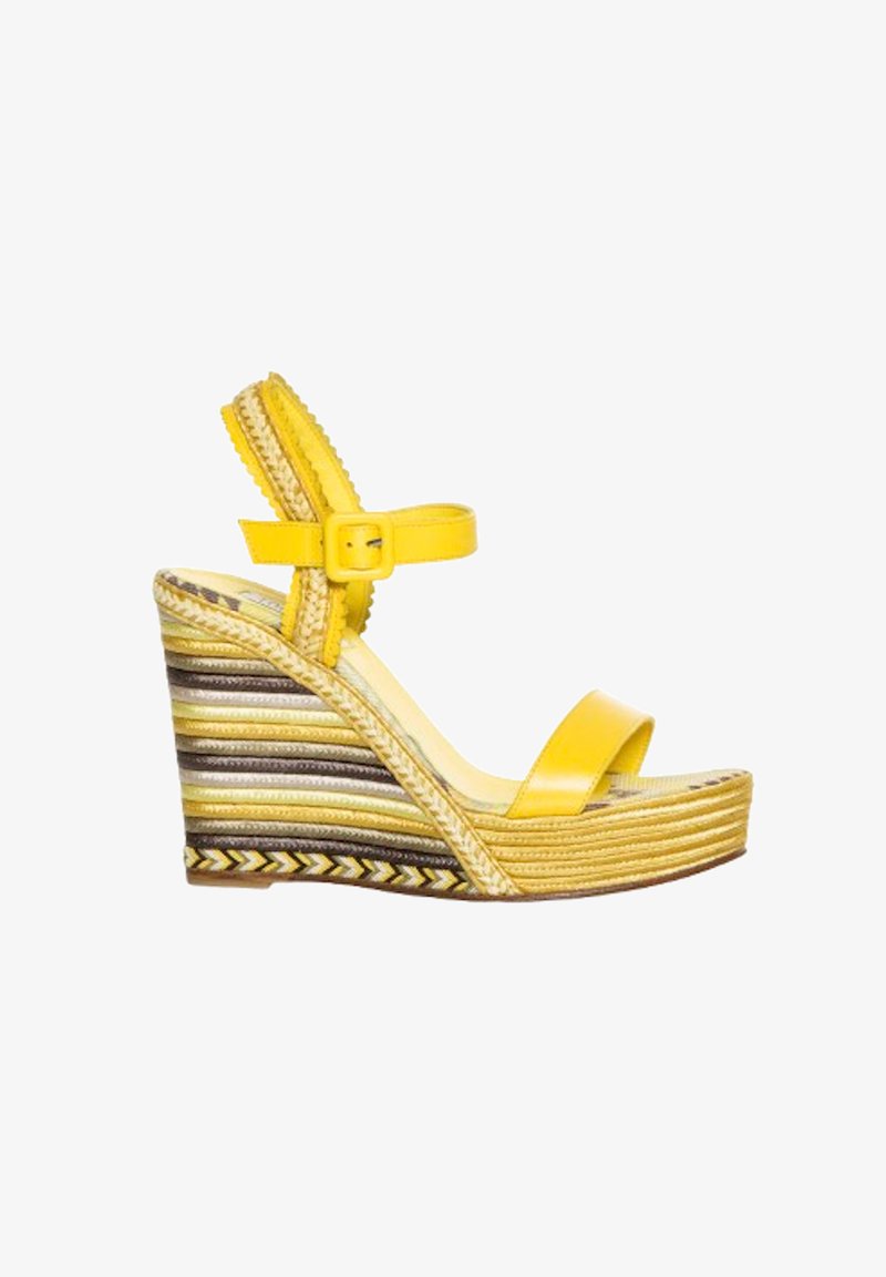 Sandalia cuña amarilla con una tira ancha sobre los dedos, correa ajustable en el tobillo y plataforma tejida texturizada de varios colores.