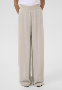 Beige wide-leg pants made of a soft, shimmery fabric with a high elastic waistband and side pockets. Smooth texture with a flowing design.