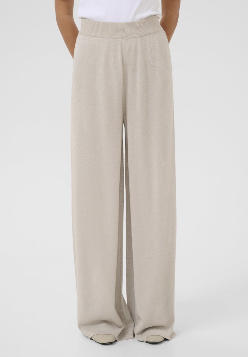 Beige wide-leg pants made of a soft, shimmery fabric with a high elastic waistband and side pockets. Smooth texture with a flowing design.