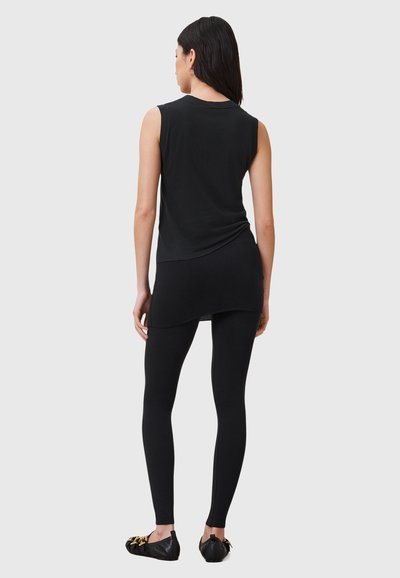 Haut noir sans manches et leggings, confectionnés dans un tissu doux et extensible. Le haut présente un ourlet incurvé, et les leggings sont ajustés au corps.