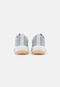 Ljusblå sneakers med en slät yta, vita accenter, en dämpad sula och en bakre dragflik för enkel påtagning.