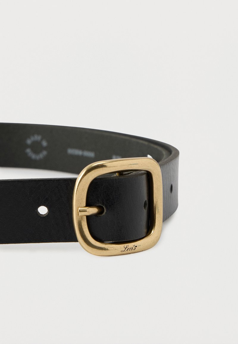 Cintura in pelle nera con fibbia quadrata in metallo dorato incisa con la scritta "Levi's", posata distesa su uno sfondo bianco.