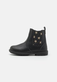 Bottines en cuir noir avec un panneau élastique latéral ornés d'étoiles dorées sur un fond noir, surface texturée et bout arrondi.