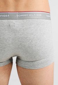 Grå bomullsboxerbriefs som har en kontrasterende rød og grå elastisk midjebånd med "TOMMY HILFIGER"-logoen trykt på.