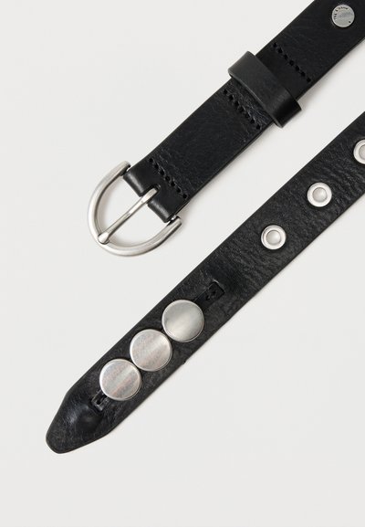 Μαύρη δερμάτινη ζώνη με ασημένια στρογγυλεμένη αγκράφα, τρεις μεγάλες ασημένιες διακοσμητικές καρφίτσες και πολλαπλές ασημένιες τρύπες σε λευκό φόντο.