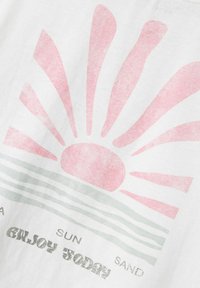 Camiseta blanca con un gráfico de sol rosa con rayos, y líneas grises debajo. El texto dice "DISFRUTA HOY" con un acabado brillante.