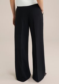 Pantaloni negri cu croi larg, confecționați dintr-un material texturat, având un tiv neted și două buzunare la spate. Design simplu și clasic.