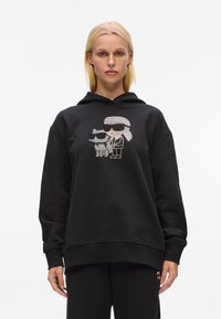 Felpa nera oversize con un design grafico di due personaggi con occhiali da sole, realizzata in morbido tessuto misto cotone.
