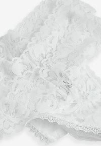 Witte kantstof met ingewikkelde bloemmotieven, geschulpte randen en een zachte, textuurrijke afwerking, geschikt voor kleding of decoratief gebruik.