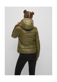 Giacca a vento verde con colletto alto e cappuccio, caratterizzata da sezioni trapuntate orizzontali e una texture liscia e lucida.
