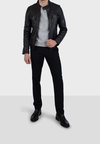 Musta nahkatakki vetoketjullisilla taskuilla, harmaa collegepaita alla, kapeat mustat housut ja mustat nilkkurit. Yksinkertainen malli ja tyylikäs siluetti.