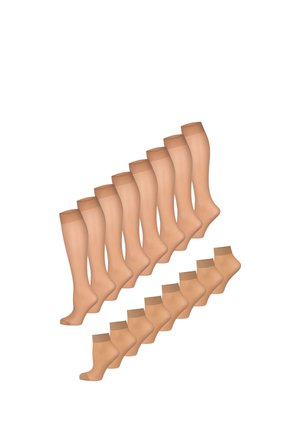 Beine, die transparente beige kniehohe Strümpfe mit einem breiten elastischen Bund oben tragen, stehen mit leicht gekreuzten Füßen.